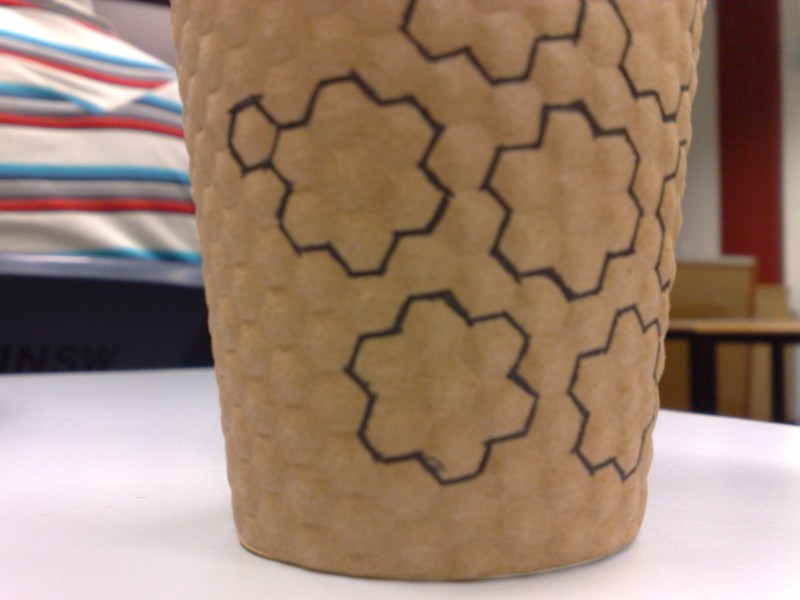 An empty coffee cup, once containing a double espresso, now with its hexagonal pattern idly traced over during a lecture about the Simplex Method.